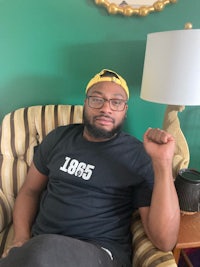 a black man sitting in a chair with a t - shirt on